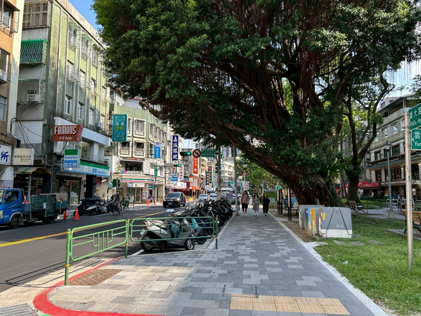 改善後的人行道：路面平整寬敞，並加裝黑色景觀護欄隔離車道，確保行人安全。